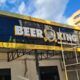 Painel preto e amarelo Beer King com estrutura de instalação visível.